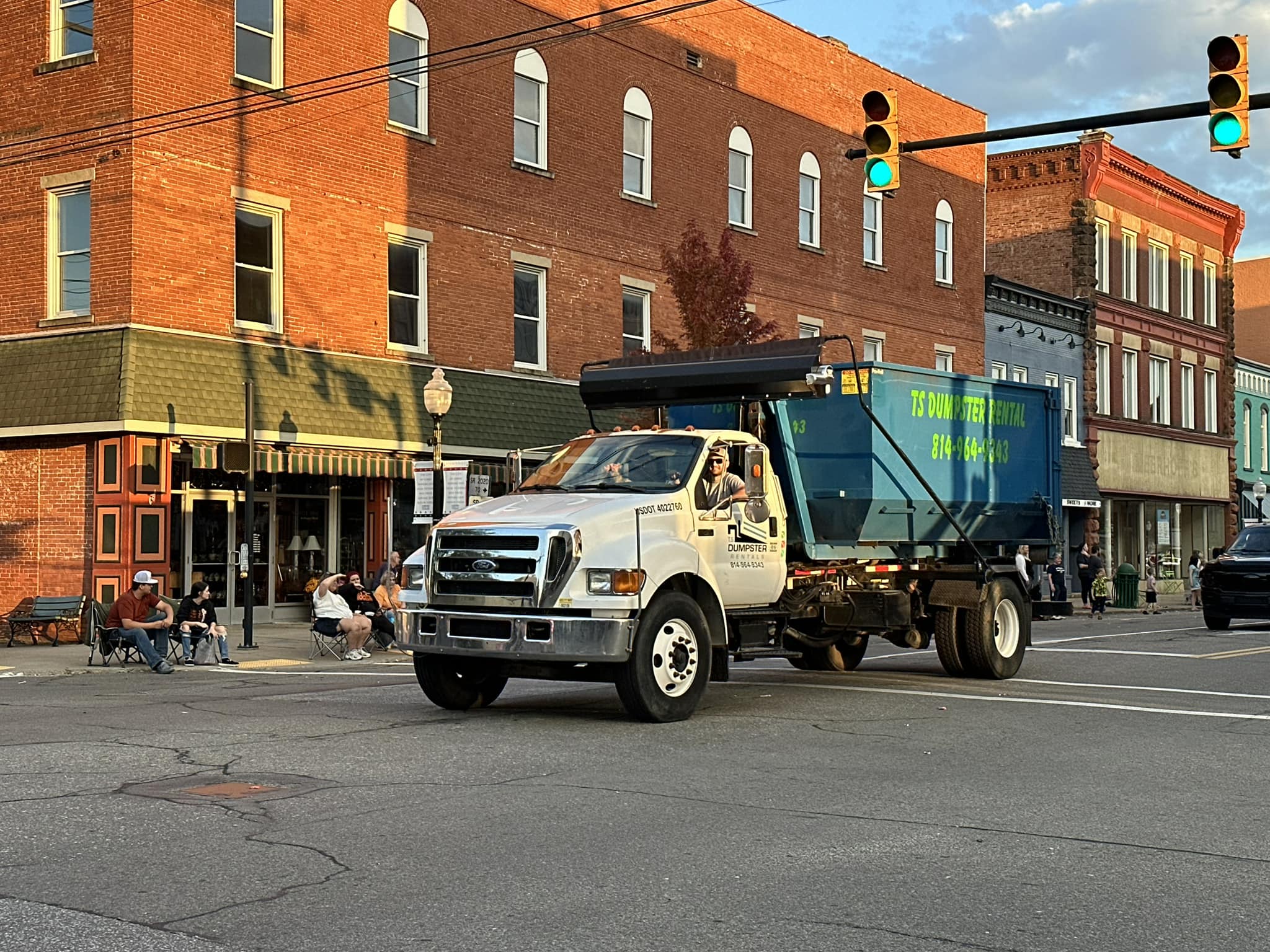 Truck driving through town with dumpster ready for delivery